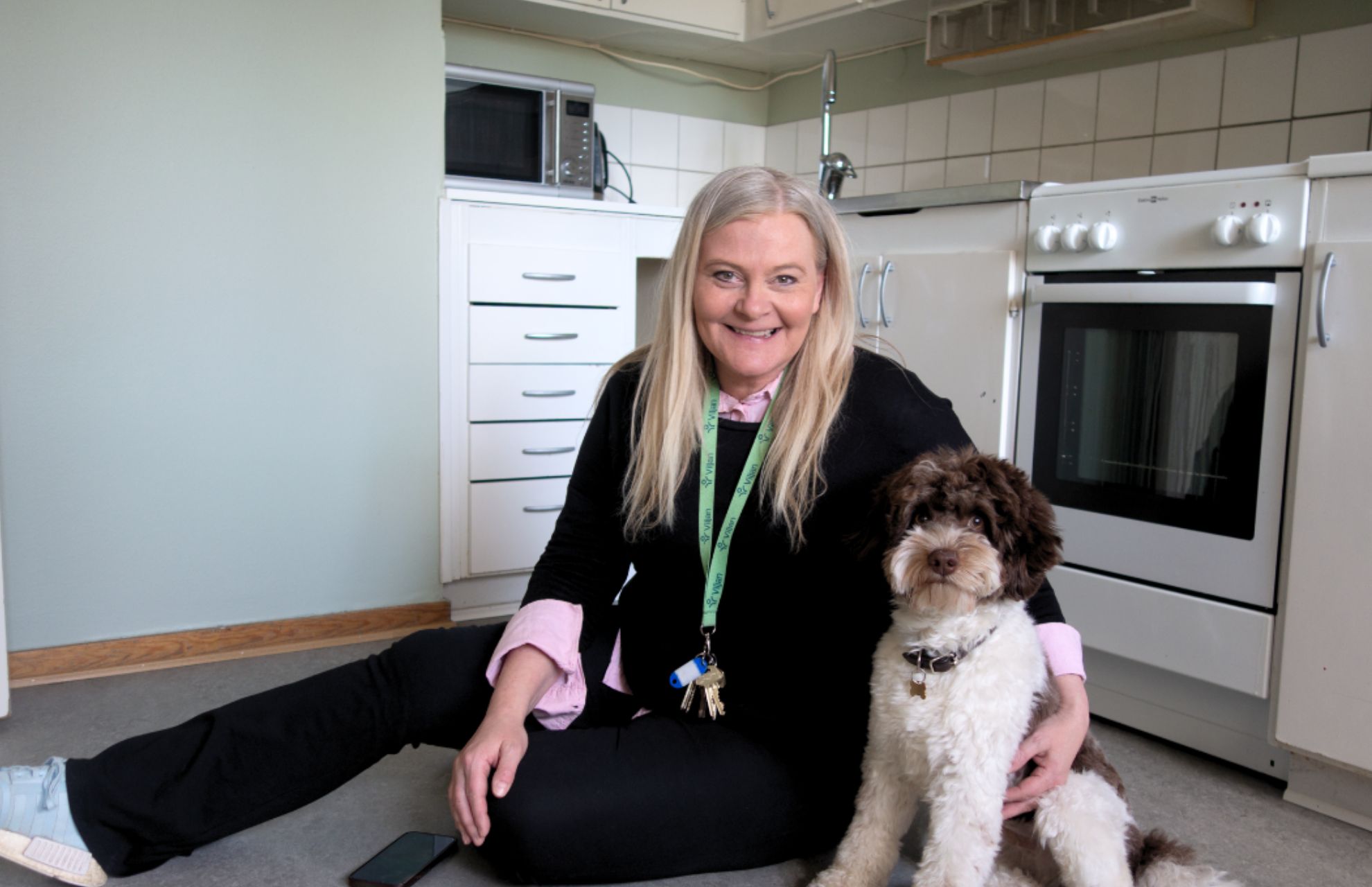 Verksamhetschef Sara sitter i köket i en av lägenheterna, tillsammans med en hund