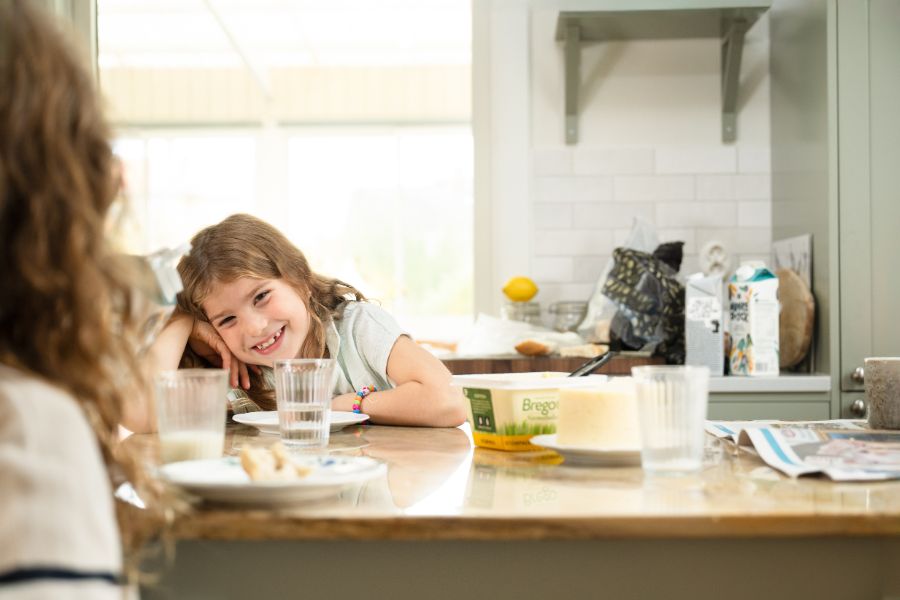 Leende flicka vid frukostbord