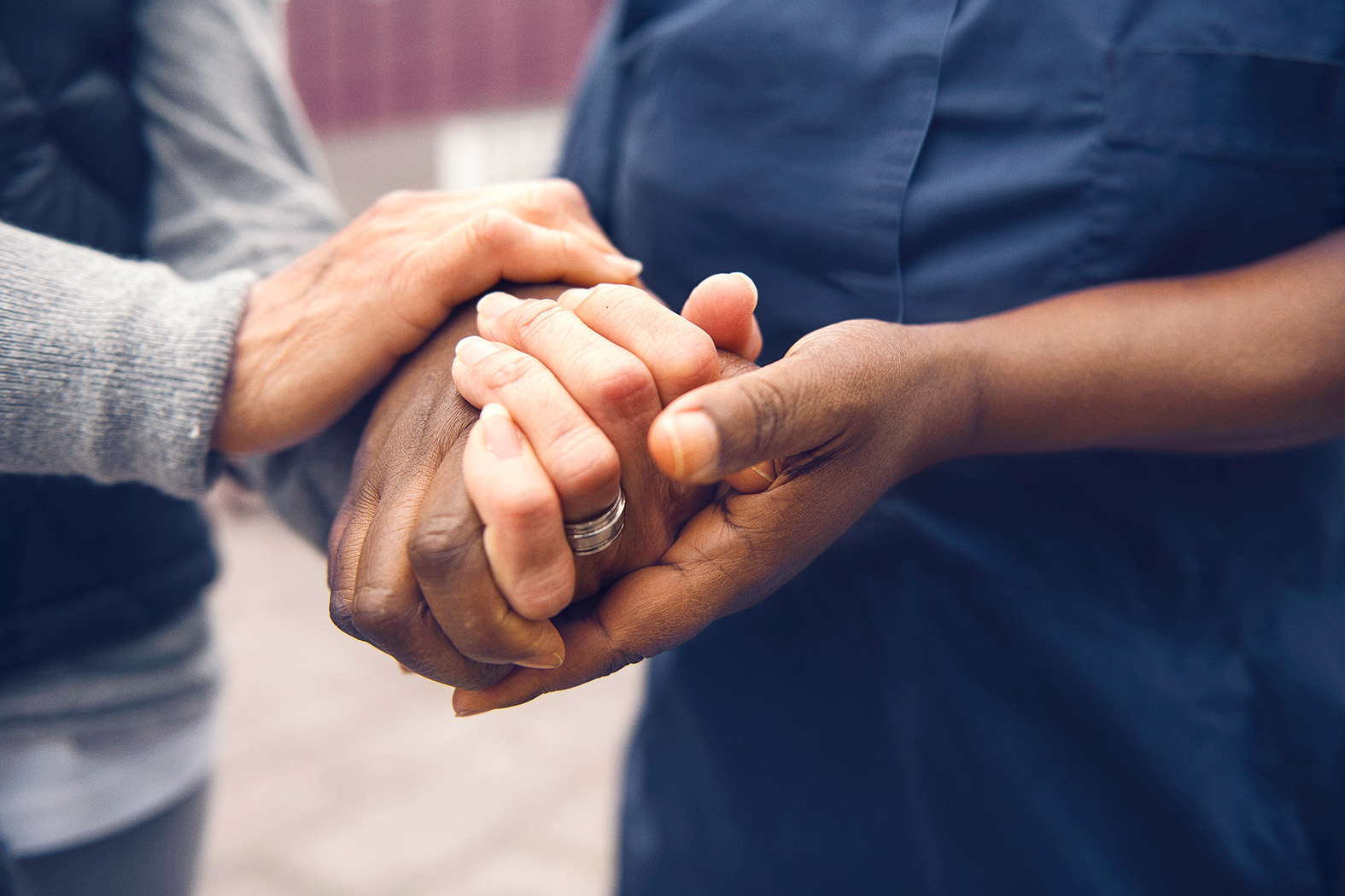 Personer håller varandras händer i en stödjande gest, symboliserar omsorg och gemenskap