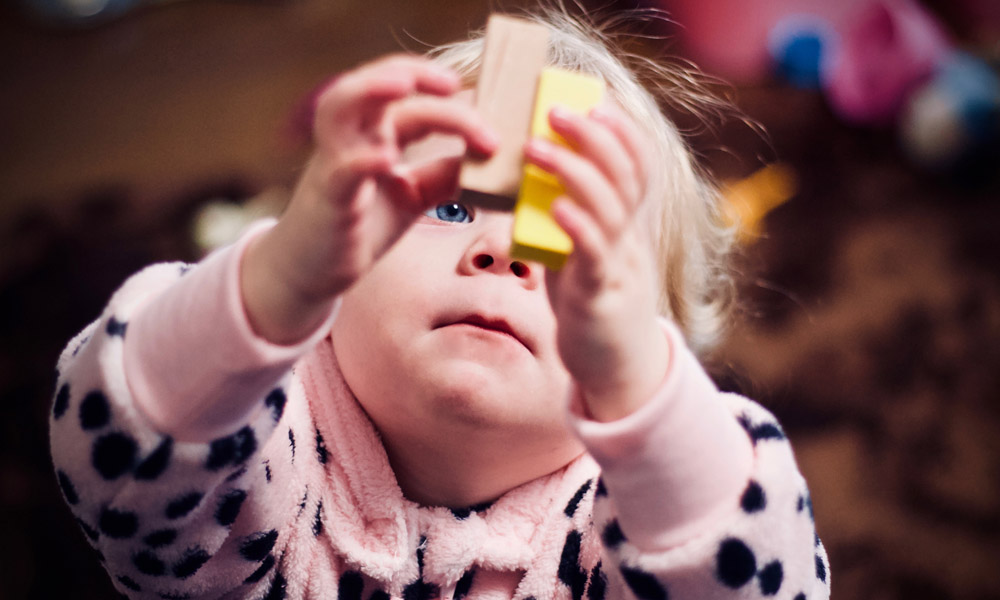 Småbarn i prickig pyjamas leker med färgglada byggklossar inomhus