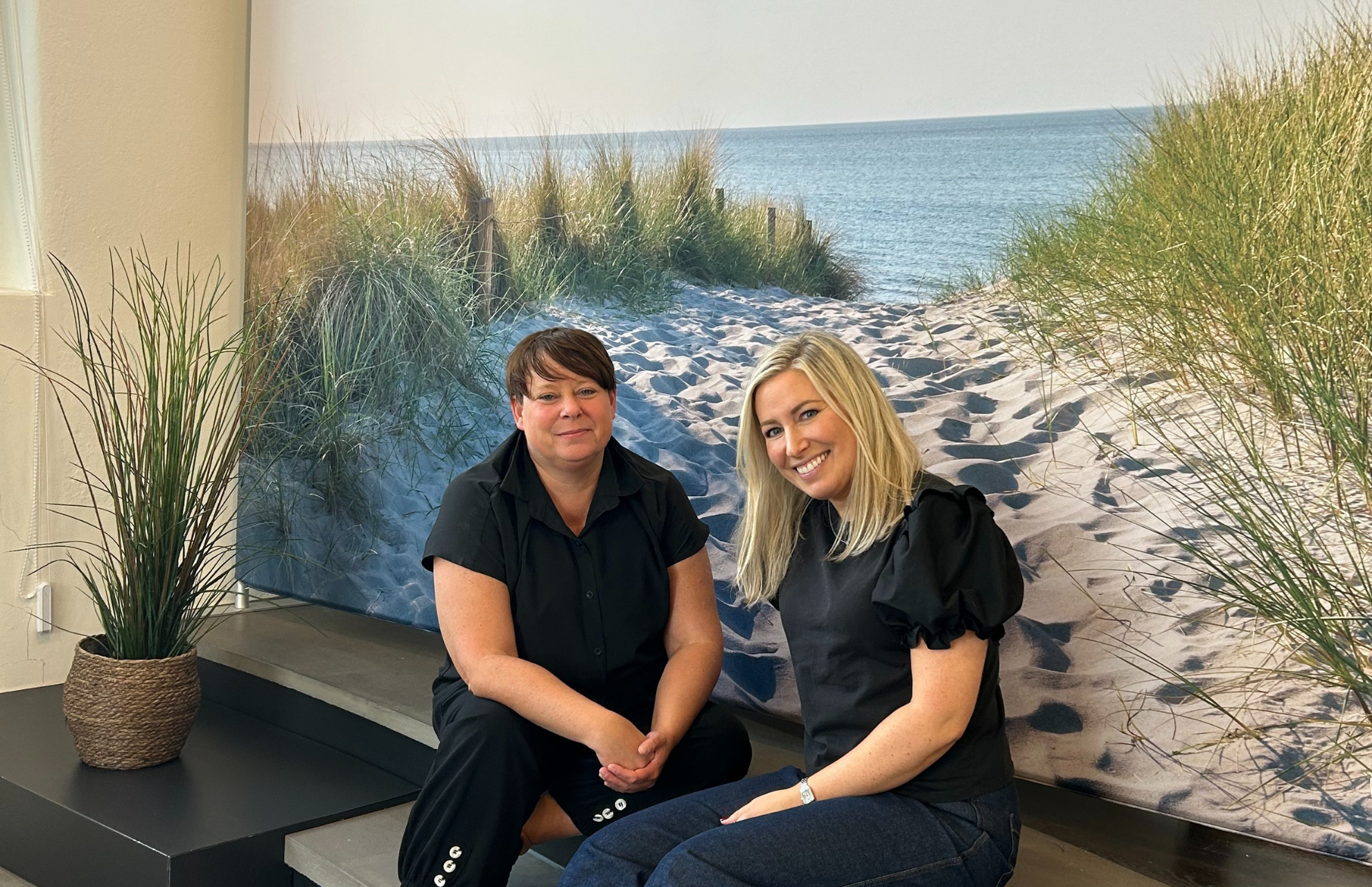 Veronika och Stina från Viljans metodteam sitter framför en vägg med en strandmålning