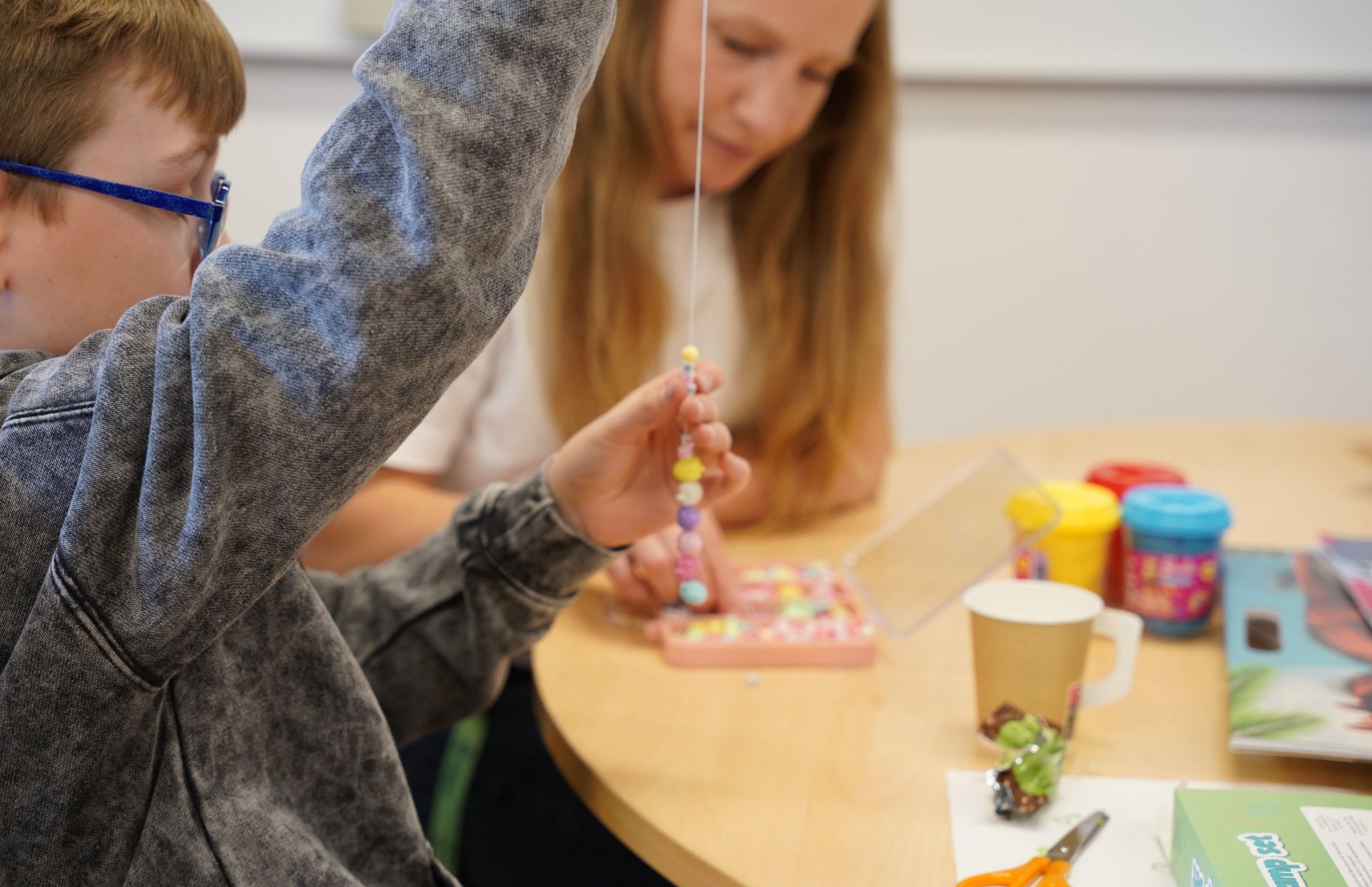 Barn pysslar p&aring; familjehemsdagen, s&auml;tter p&auml;rlor p&aring; tr&aring;d