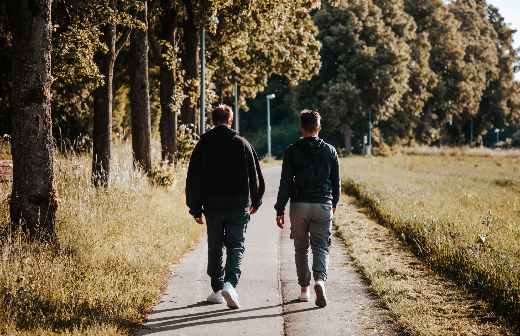 Två män promenerar bortåt på väg i lantlig miljö