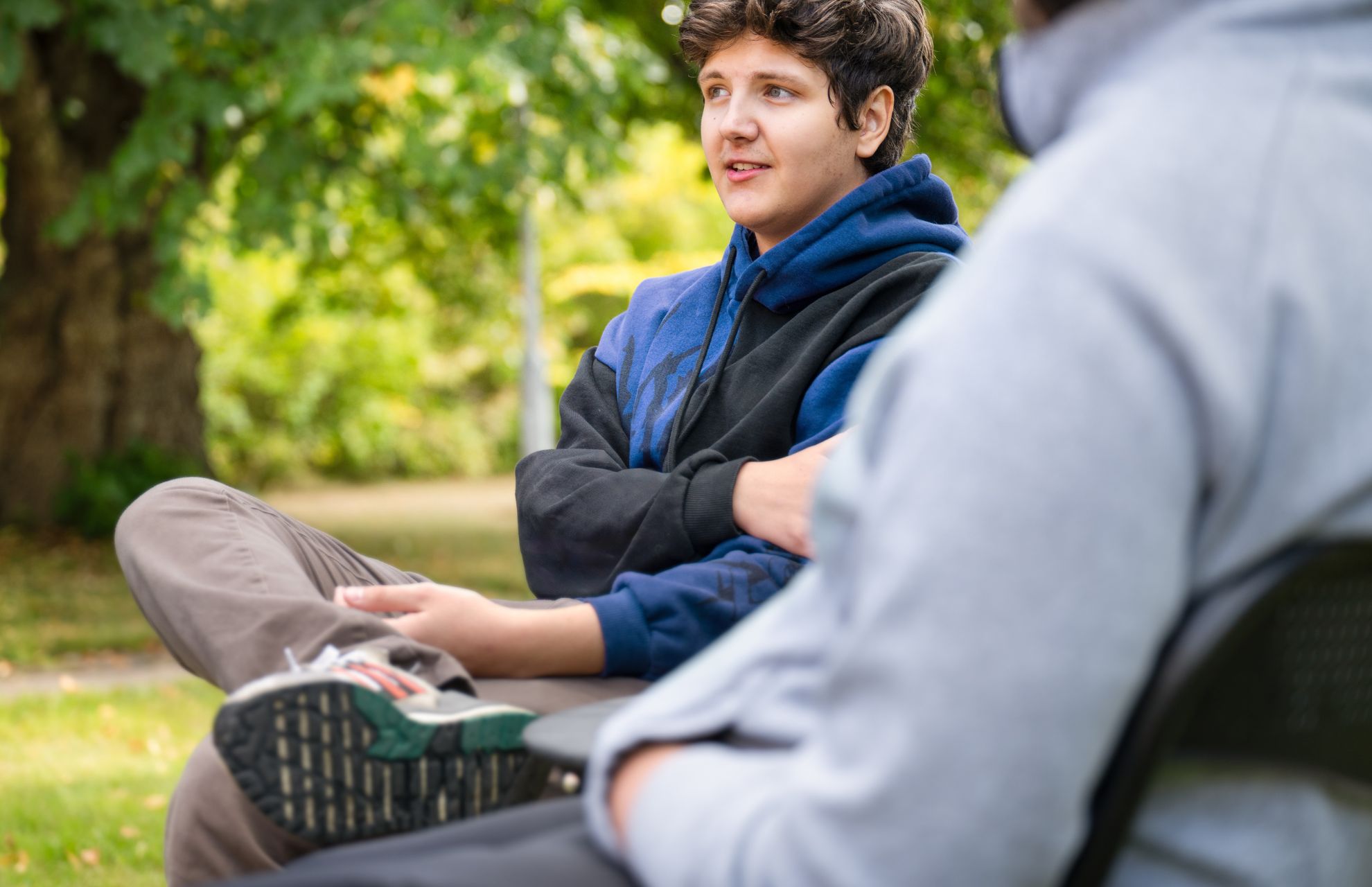 Elev på skolan i samtal med en vuxen, sitter ute i grönska