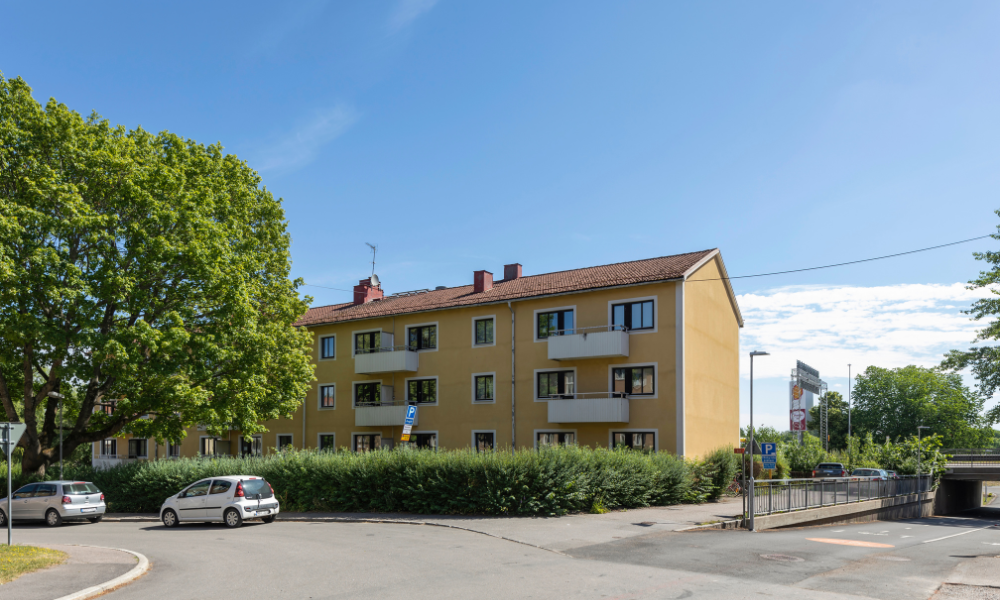 Gul byggnad från gatan, gröna träd, solig dag