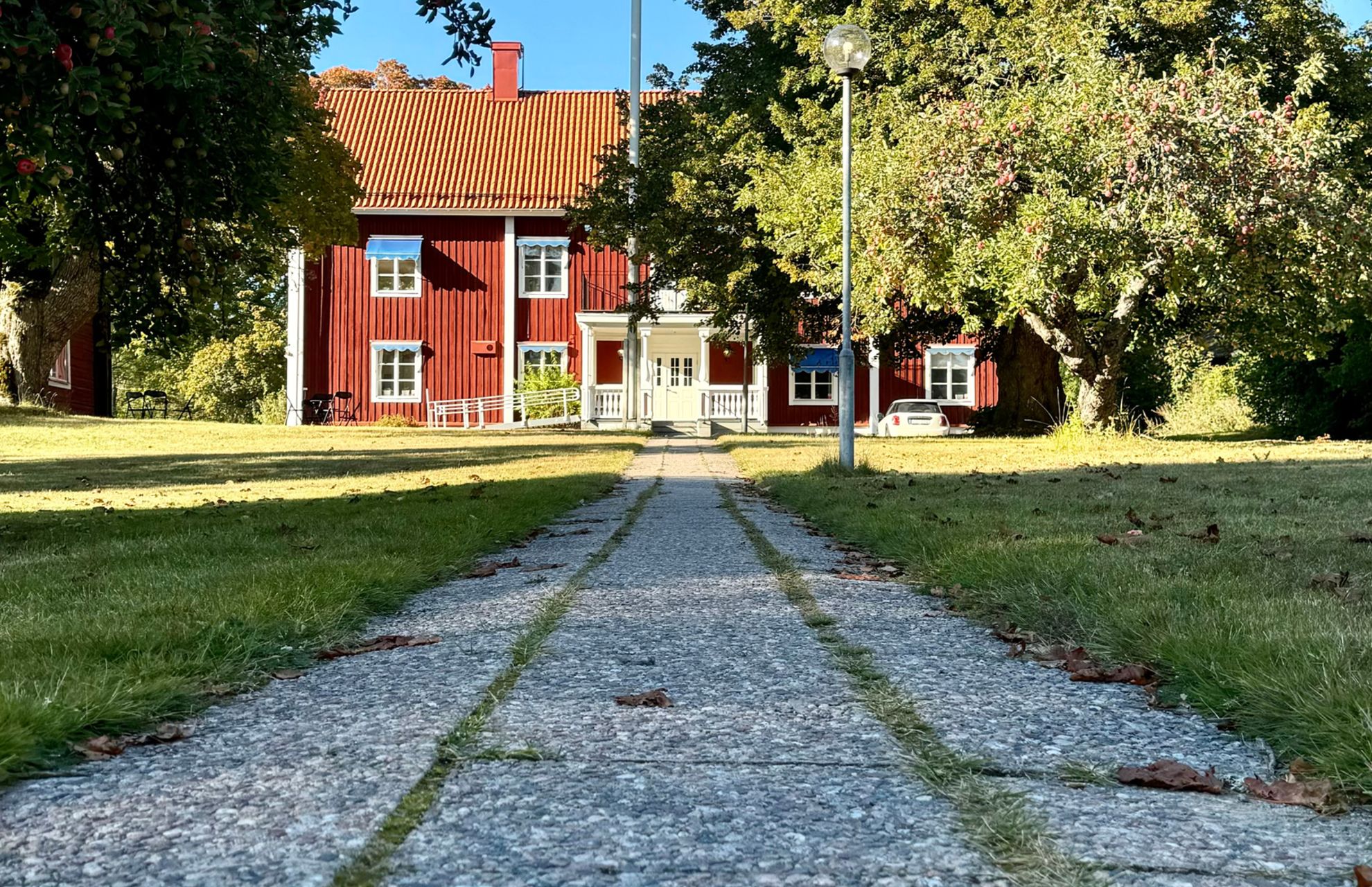 Skolan som är ett rött äldre hus, omslutet av grönska en solig dag