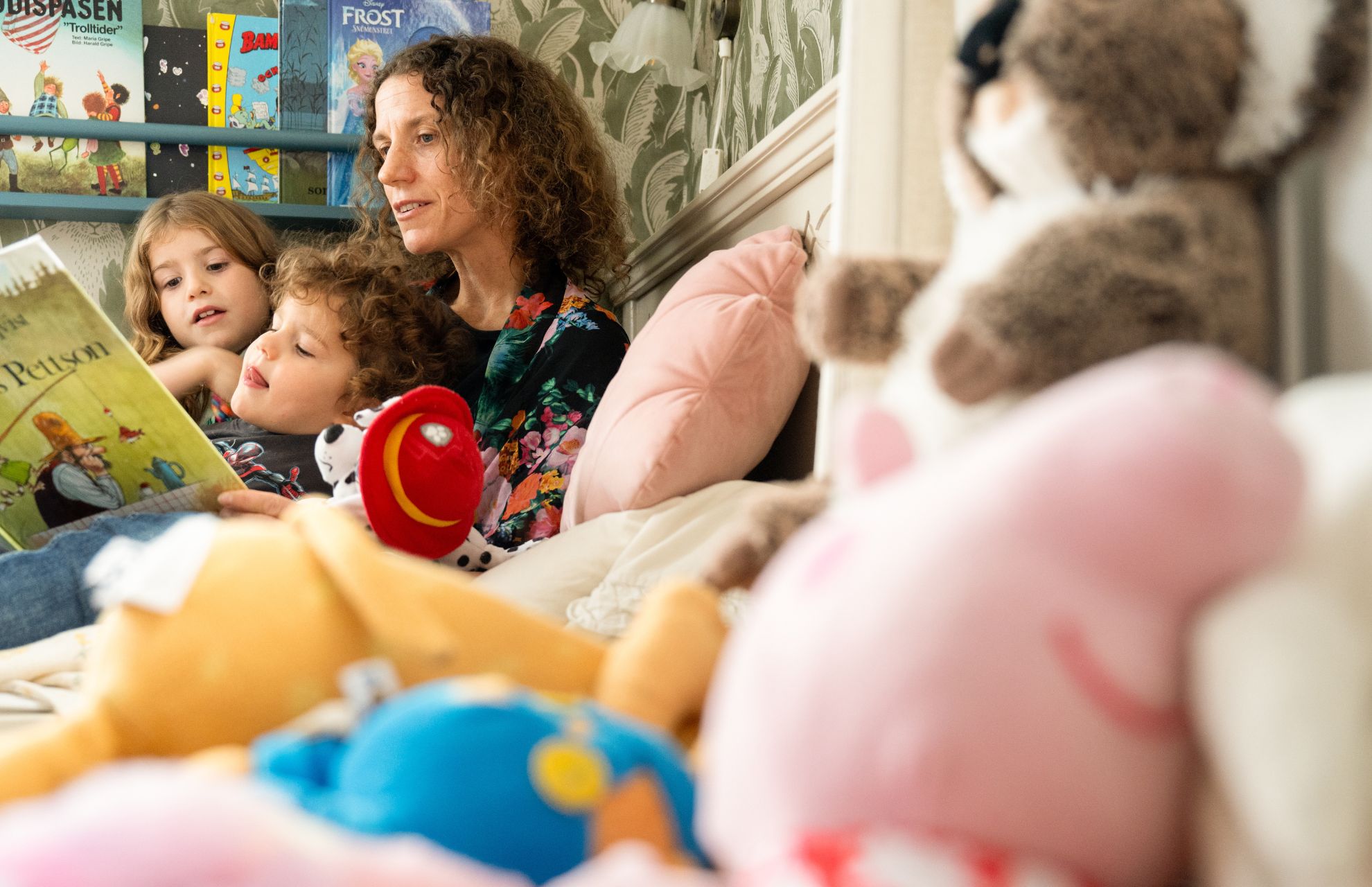 Fyra personer sitter på en gräsmatta och njuter av höstvädret med träd i orange och gula nyanser i bakgrunden